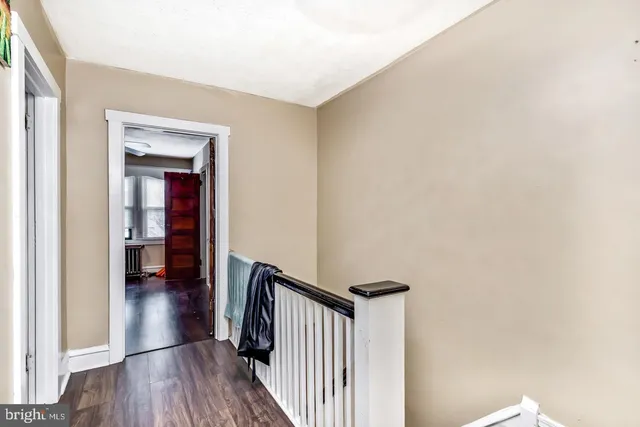 a view of a hallway with wooden floor and a bathroom