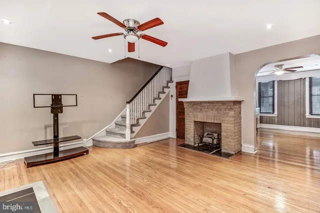 a view of a livingroom with a fireplace a ceiling fan and windows