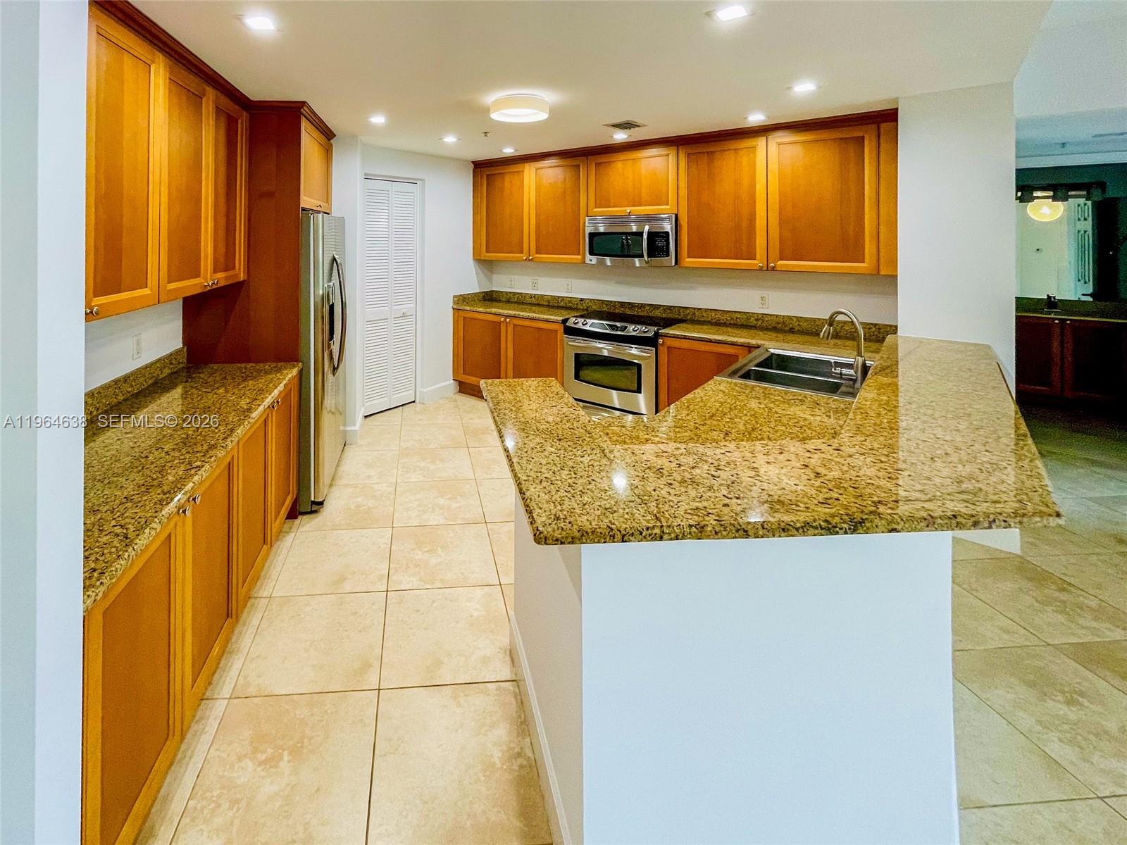 55 Merrick Way, Unit 715 Coral Gables, FL 33134 - Photo 28 of 52 a kitchen with stainless steel appliances granite countertop a sink and a refrigerator