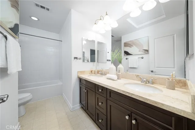 a spacious bathroom with a granite countertop sink a toilet a mirror and shower