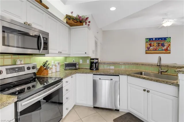 a kitchen with white cabinets a sink dishwasher and a stove with wooden floor