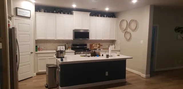 a kitchen with stainless steel appliances a sink a stove a refrigerator and cabinets