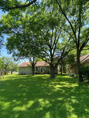 a view of an house with backyard and trees