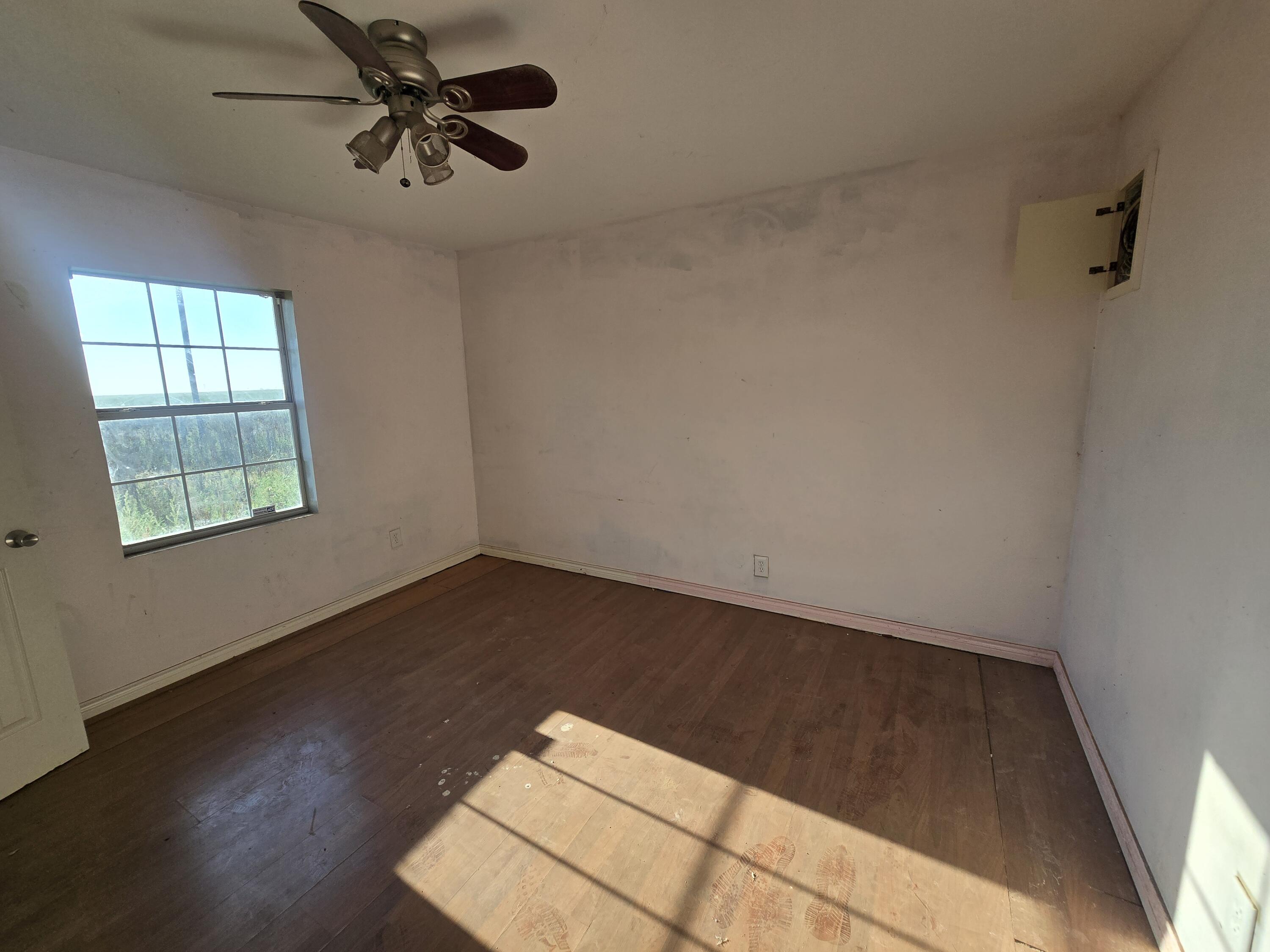 1611 County Road 50 Plainview, TX 79072 - Photo 7 of 11 an empty room with wooden floor fan and windows