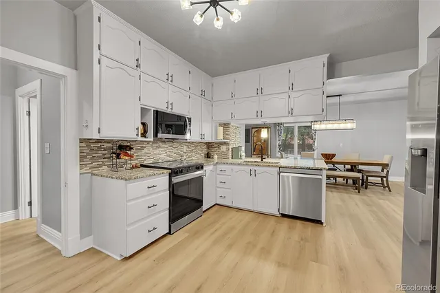 a kitchen with granite countertop a stove a sink and a refrigerator