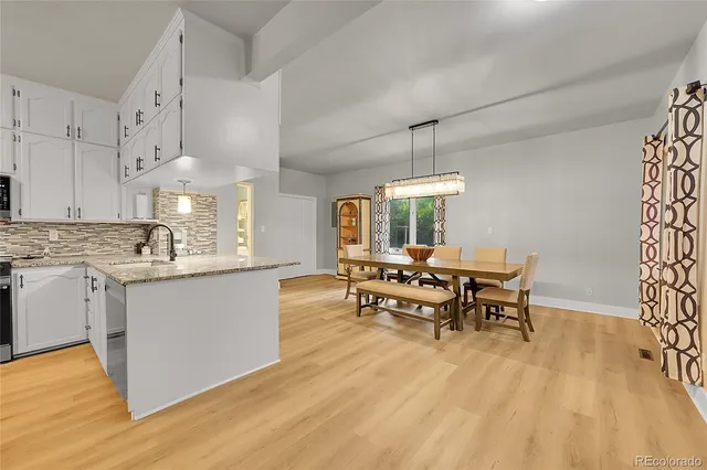 a kitchen with stainless steel appliances a dining table chairs and granite counter tops