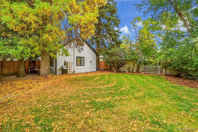 a backyard of a house with table and chairs under an umbrella