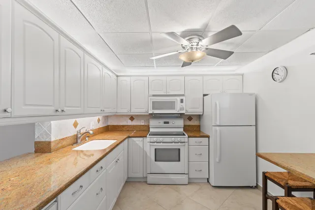 a kitchen with granite countertop white cabinets and white appliances