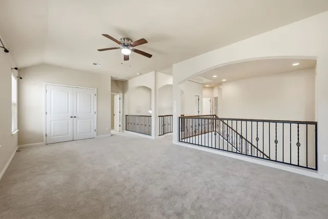 an empty room with staircase and ceiling fan