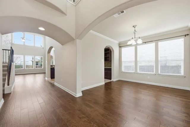 a view of an empty room with window and wooden floor