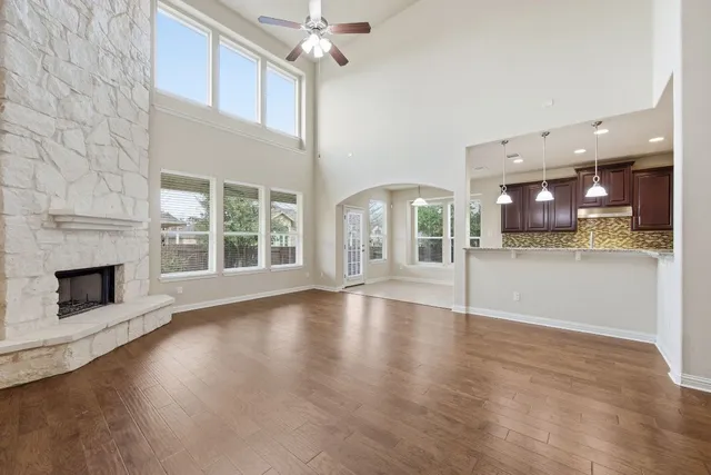 an empty room with wooden floor fireplace and windows