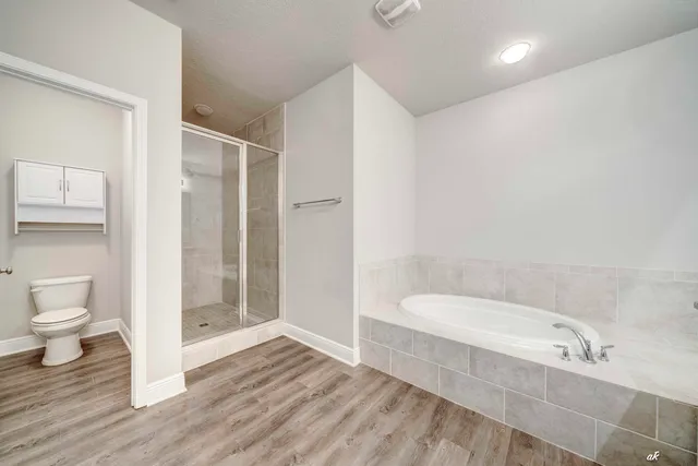 a view of an empty room with wooden floor and a ceiling fan