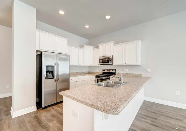 a kitchen with stainless steel appliances granite countertop a refrigerator a stove a sink and a microwave