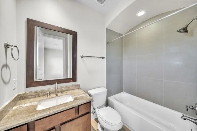 a bathroom with a granite countertop sink toilet and mirror