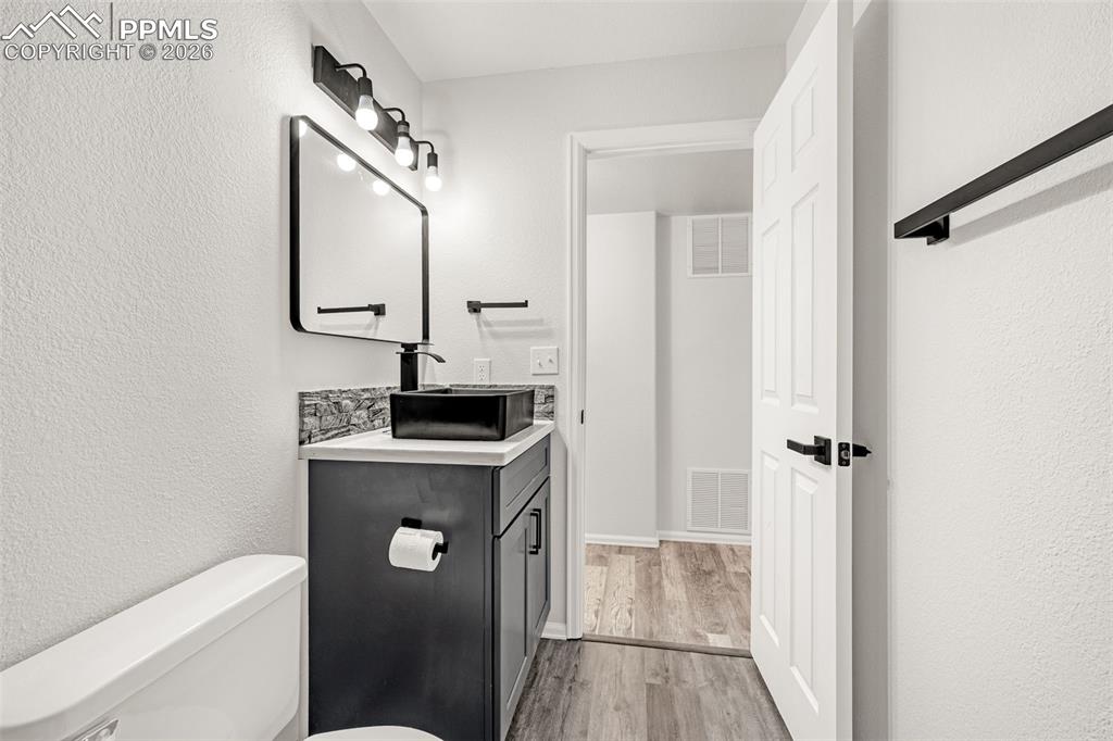 8388 Fort Smith Road Peyton, CO 80831 - Photo 41 of 49 a bathroom with a granite countertop sink a toilet and a mirror