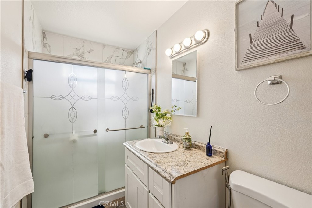 975 Brookside Avenue Redlands, CA 92373 - Photo 15 of 20 a bathroom with a granite countertop sink a toilet and shower