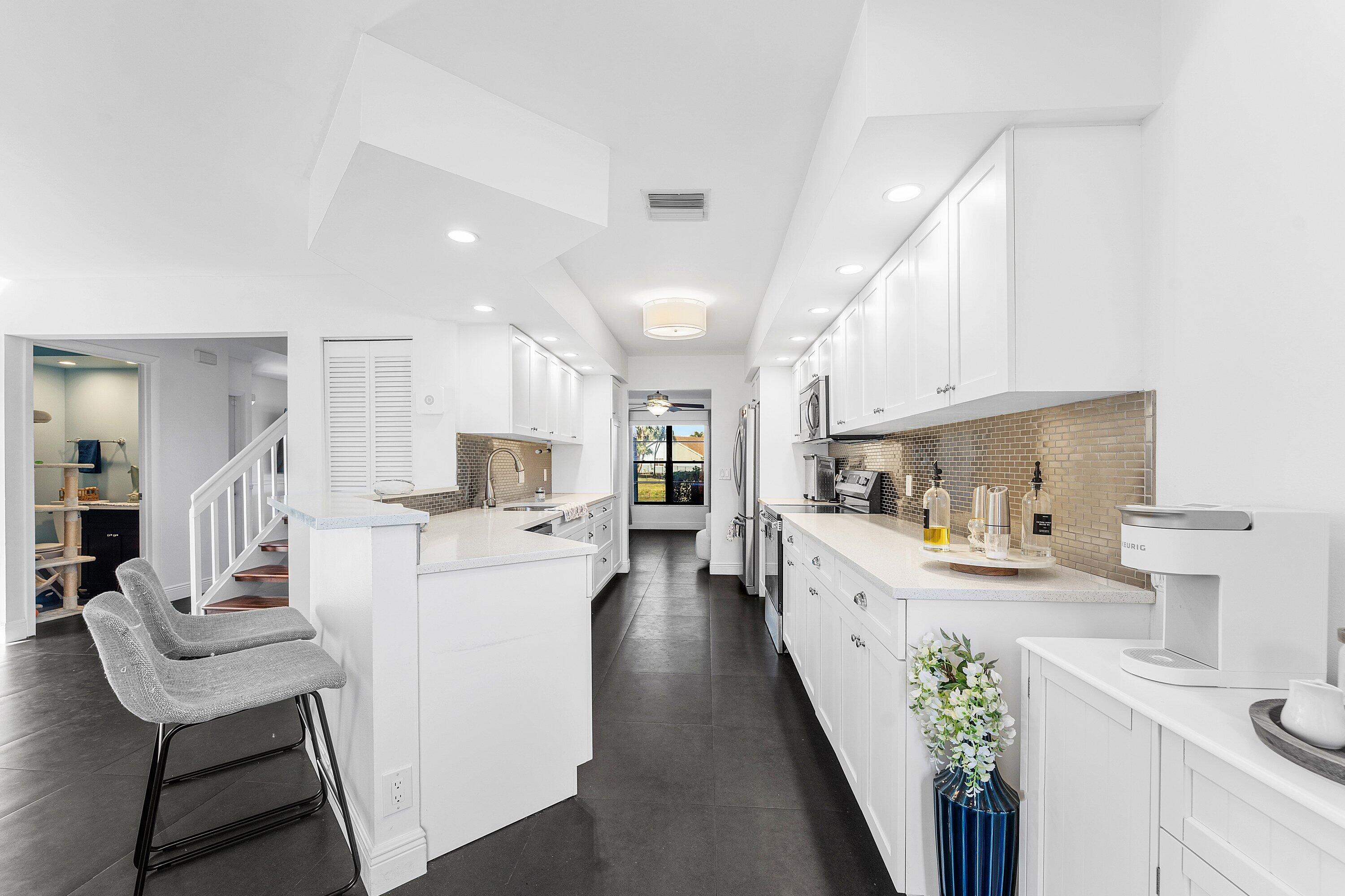 19931 Villa Lante Place Boca Raton, FL 33434 - Photo 13 of 49 a kitchen with white cabinets and stainless steel appliances
