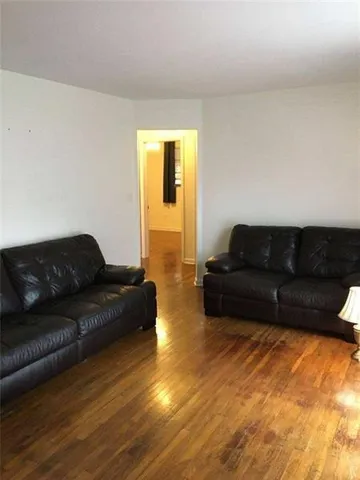 a living room with couches and kitchen view with wooden floor