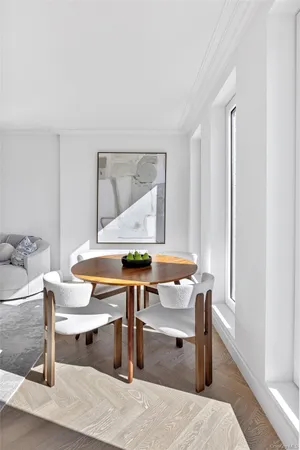 a room with table chairs wooden floor and windows
