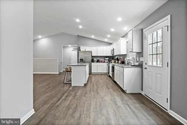 a kitchen with kitchen island wooden floors appliances and white cabinets