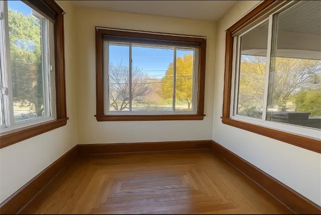 a view of an empty room with a window and wooden floor