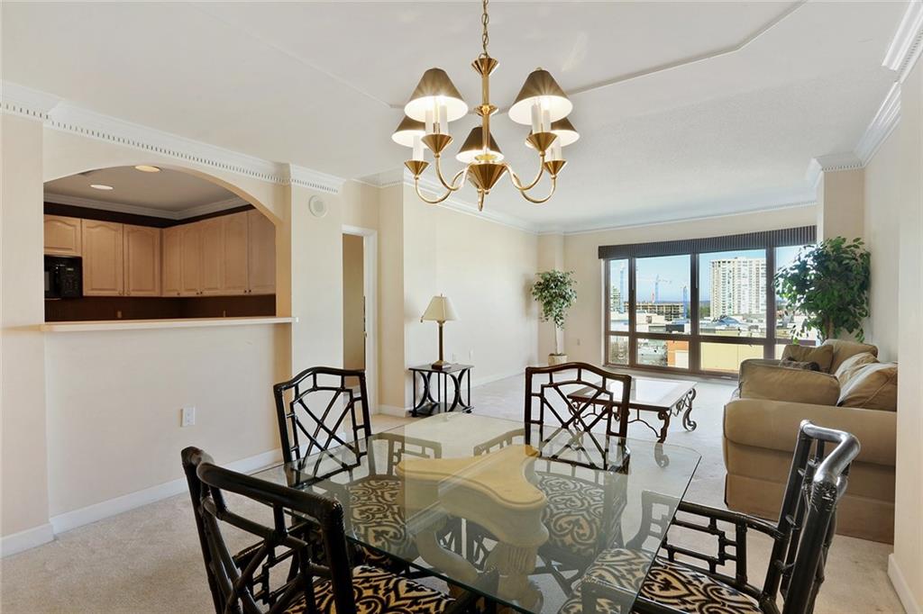 a view of a dining room with furniture a chandelier and large windows
