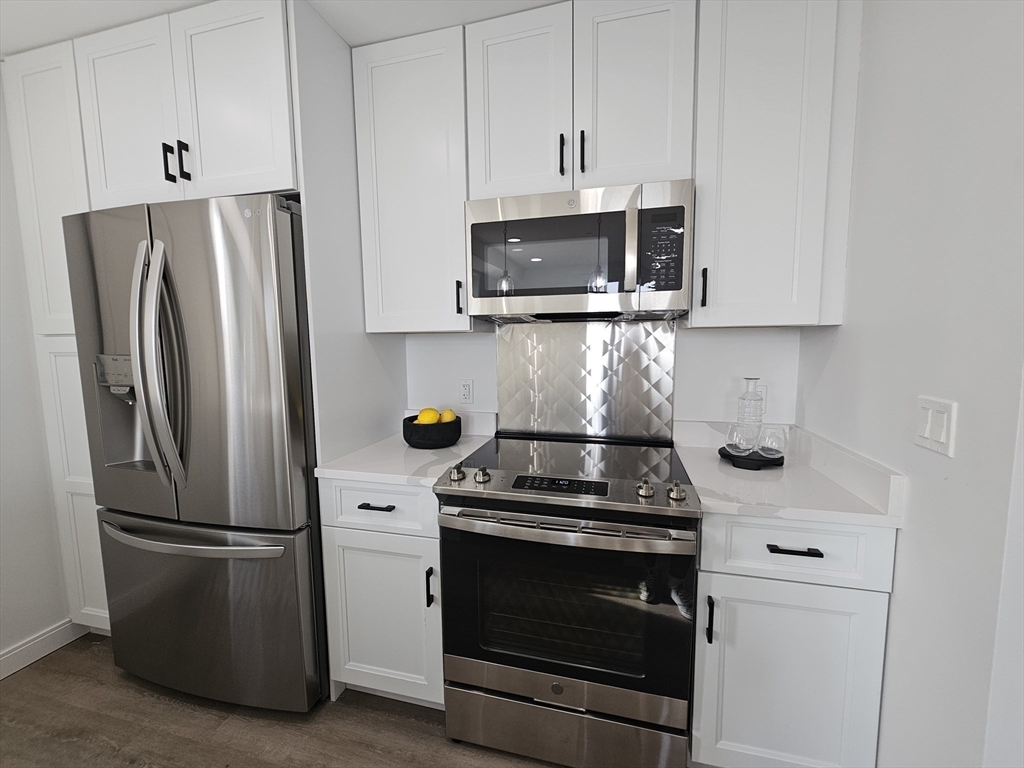 64 Alpine Street, Unit 304 Boston, MA 02119 - Photo 4 of 23 a kitchen with stainless steel appliances a refrigerator stove and microwave