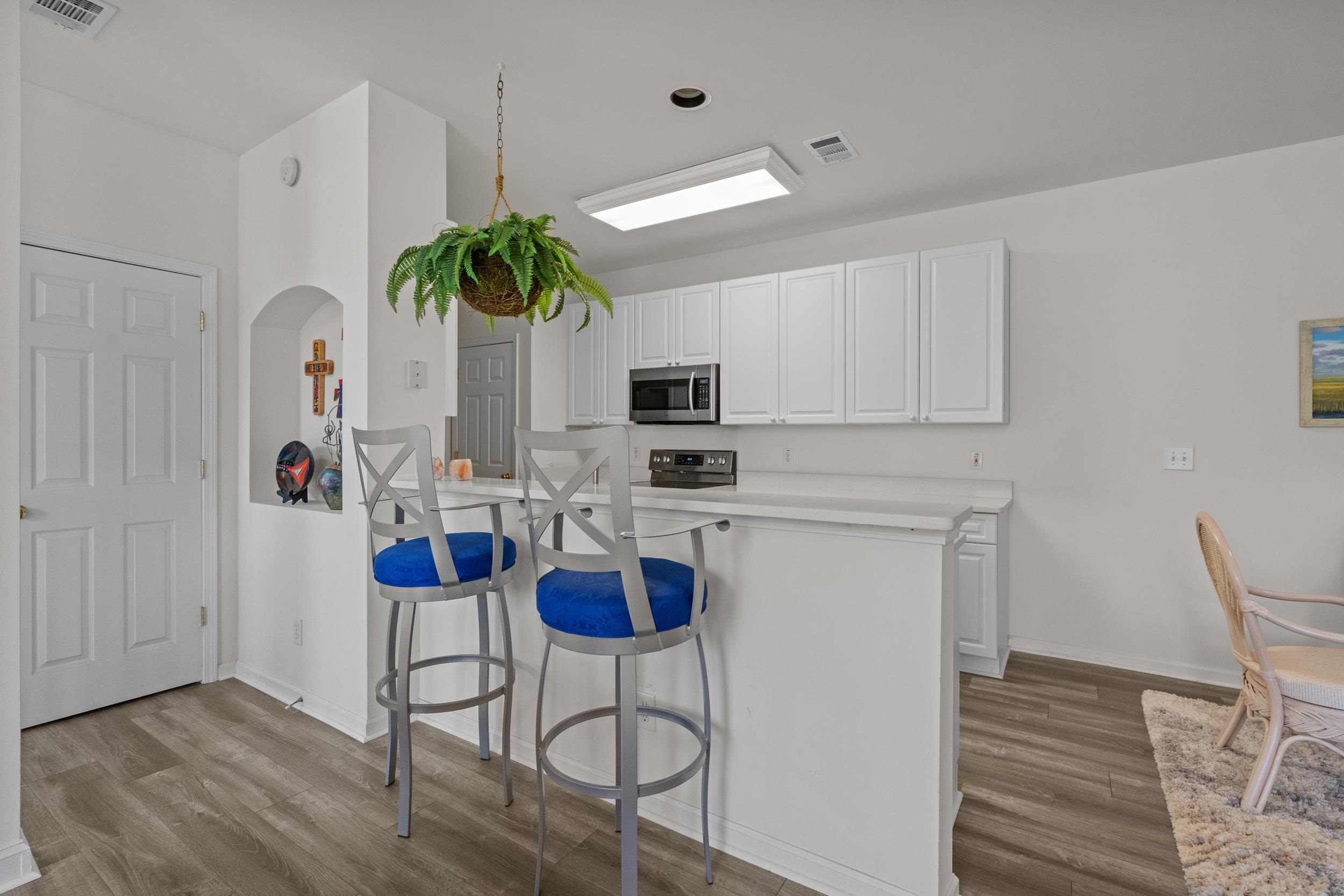 4436 Lady Banks Lane, Unit D2 Murrells Inlet, SC 29576 - Photo 7 of 32 Kitchen with light countertops, arched walkways, white cabinets, light wood finished floors, and a breakfast bar