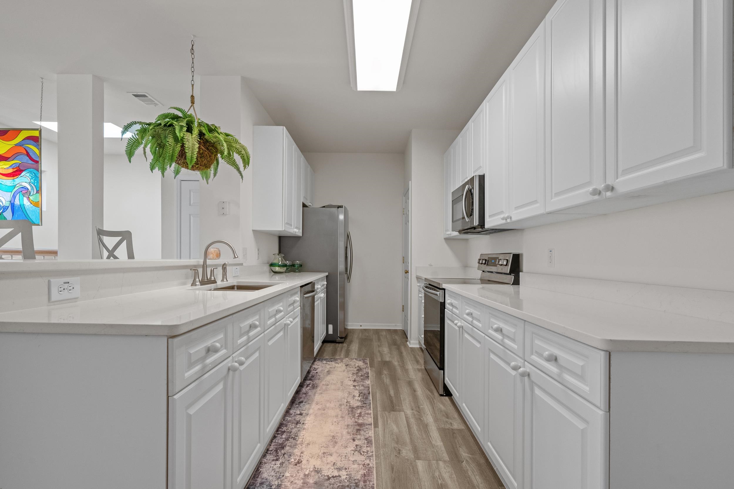 4436 Lady Banks Lane, Unit D2 Murrells Inlet, SC 29576 - Photo 8 of 32 Kitchen with appliances with stainless steel finishes, white cabinets, light stone counters, light wood-style flooring, and a peninsula