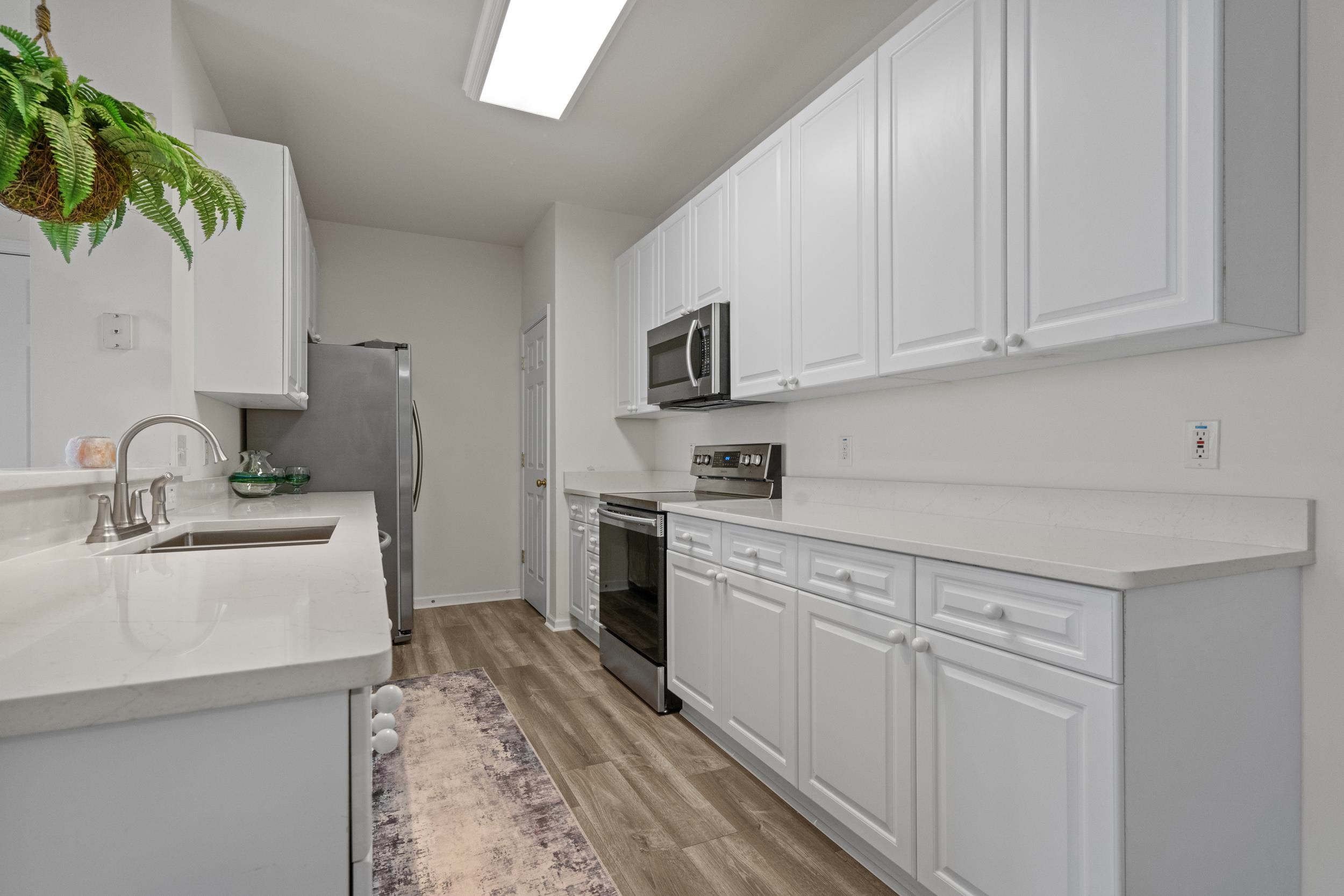 4436 Lady Banks Lane, Unit D2 Murrells Inlet, SC 29576 - Photo 9 of 32 Kitchen featuring appliances with stainless steel finishes, white cabinetry, light stone countertops, and light wood-style floors