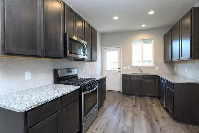 a kitchen with granite countertop stainless steel appliances a stove sink and cabinets