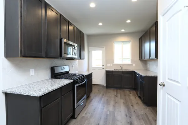 a kitchen with granite countertop stainless steel appliances a stove sink and cabinets