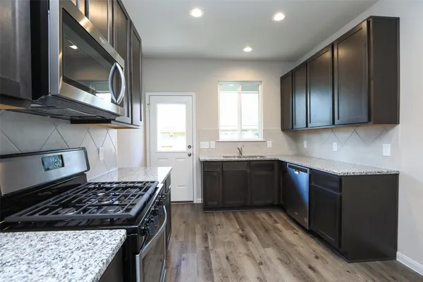 a kitchen with stainless steel appliances granite countertop a stove a sink and a microwave