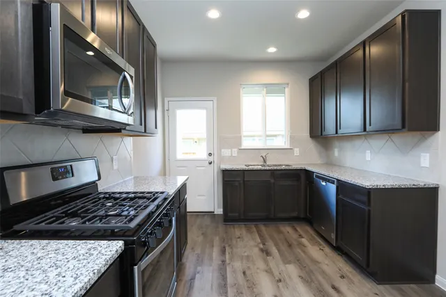 a kitchen with stainless steel appliances granite countertop a stove a sink and a microwave