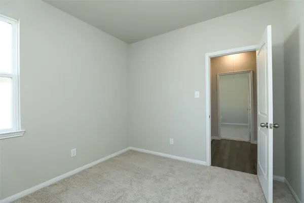 a view of an empty room with closet and a window