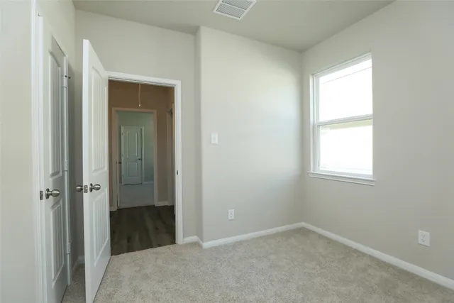 a view of an empty room with closet and a window