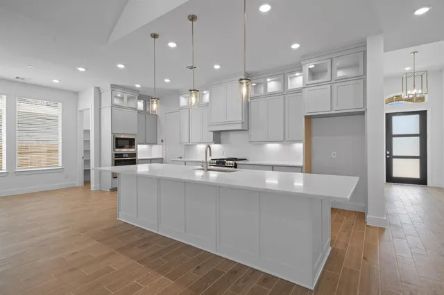 a large kitchen with kitchen island a sink a center island stainless steel appliances and a window