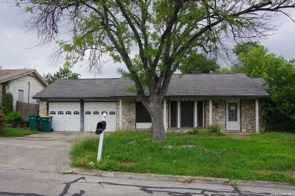 a front view of a house with a garden and trees