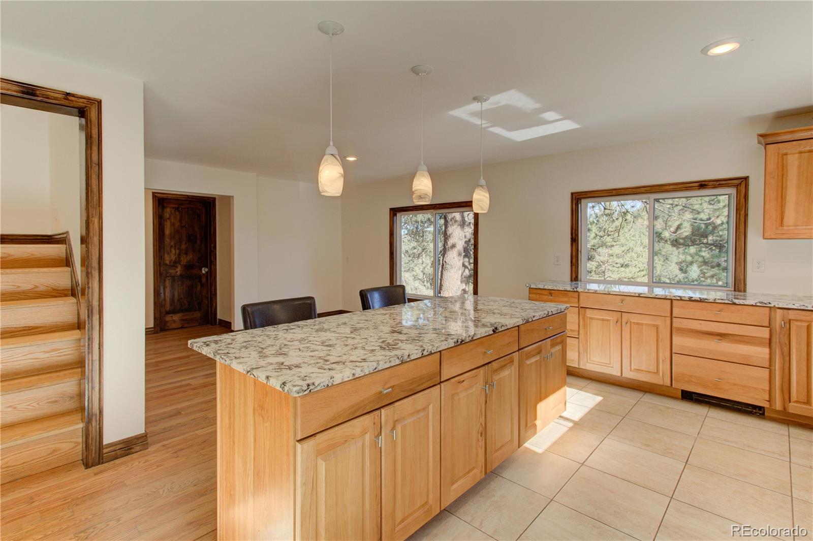 30305 Lone Spruce Road Evergreen, CO 80439 - Photo 12 of 40 a large kitchen with kitchen island granite countertop a stove a sink a refrigerator and white cabinets with wooden floor