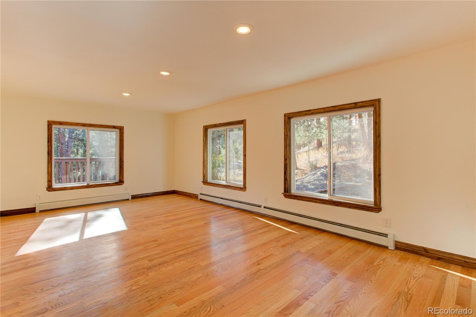 30305 Lone Spruce Road Evergreen, CO 80439 - Photo 17 of 40 a view of an empty room with wooden floor and a window