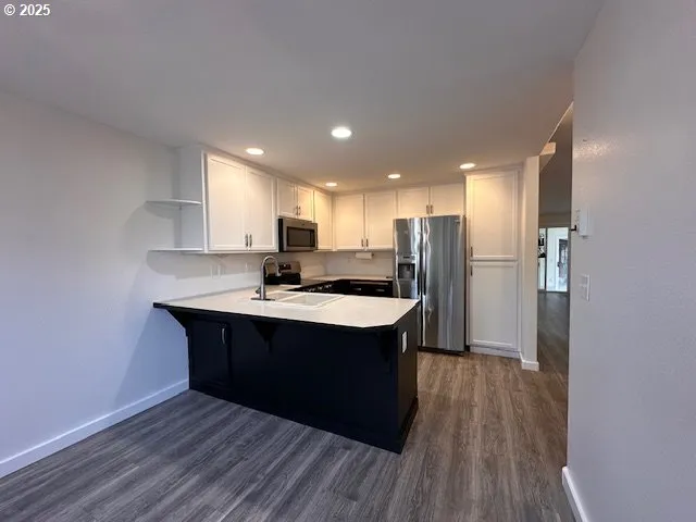 a kitchen with kitchen island a sink dishwasher a refrigerator and wooden floor