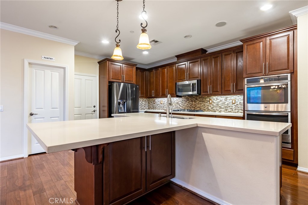 26459 Riverrock Way Saugus, CA 91350 - Photo 14 of 60 a kitchen with kitchen island granite countertop wooden cabinets a refrigerator and a sink