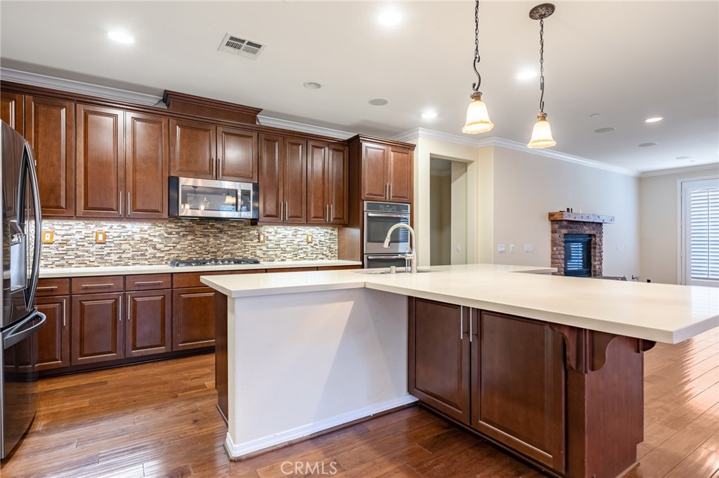 26459 Riverrock Way Saugus, CA 91350 - Photo 17 of 60 a kitchen with kitchen island granite countertop wooden cabinets a stove a sink and a refrigerator