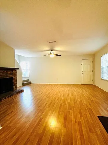 an empty room with wooden floor fireplace and windows
