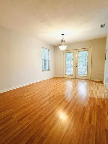 an empty room with wooden floor and windows