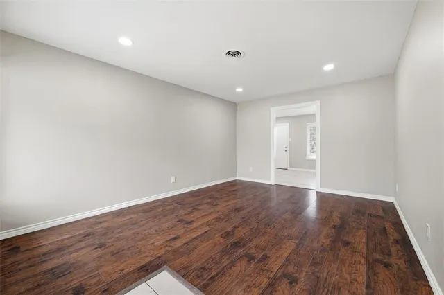 a view of an empty room with wooden floor and closet