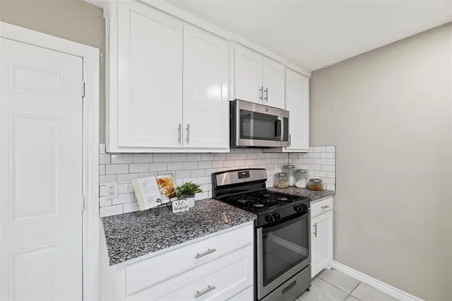 a kitchen with stainless steel appliances granite countertop white cabinets and a stove