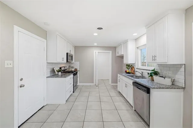 a kitchen with a sink a stove top oven and white cabinets