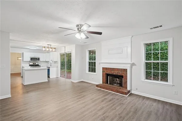 a view of an empty room with window and kitchen view