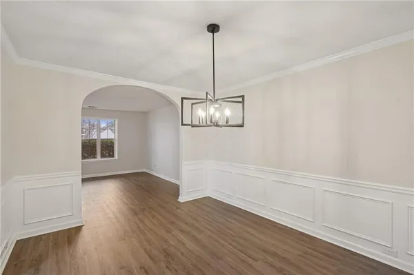 a view of empty room with wooden floor chandelier and window
